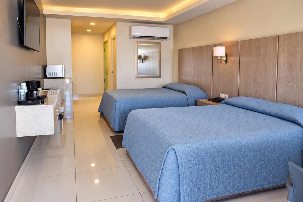 Habitación doble remodelada: dos camas con cabecera corrida de madera clara y cocineta
