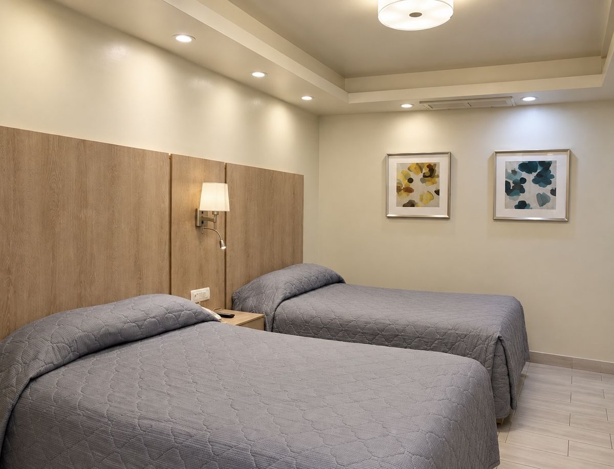 Habitación doble remodelada: dos camas con cabecera de madera clara, plafón con luz indirecta y cuadros de flores