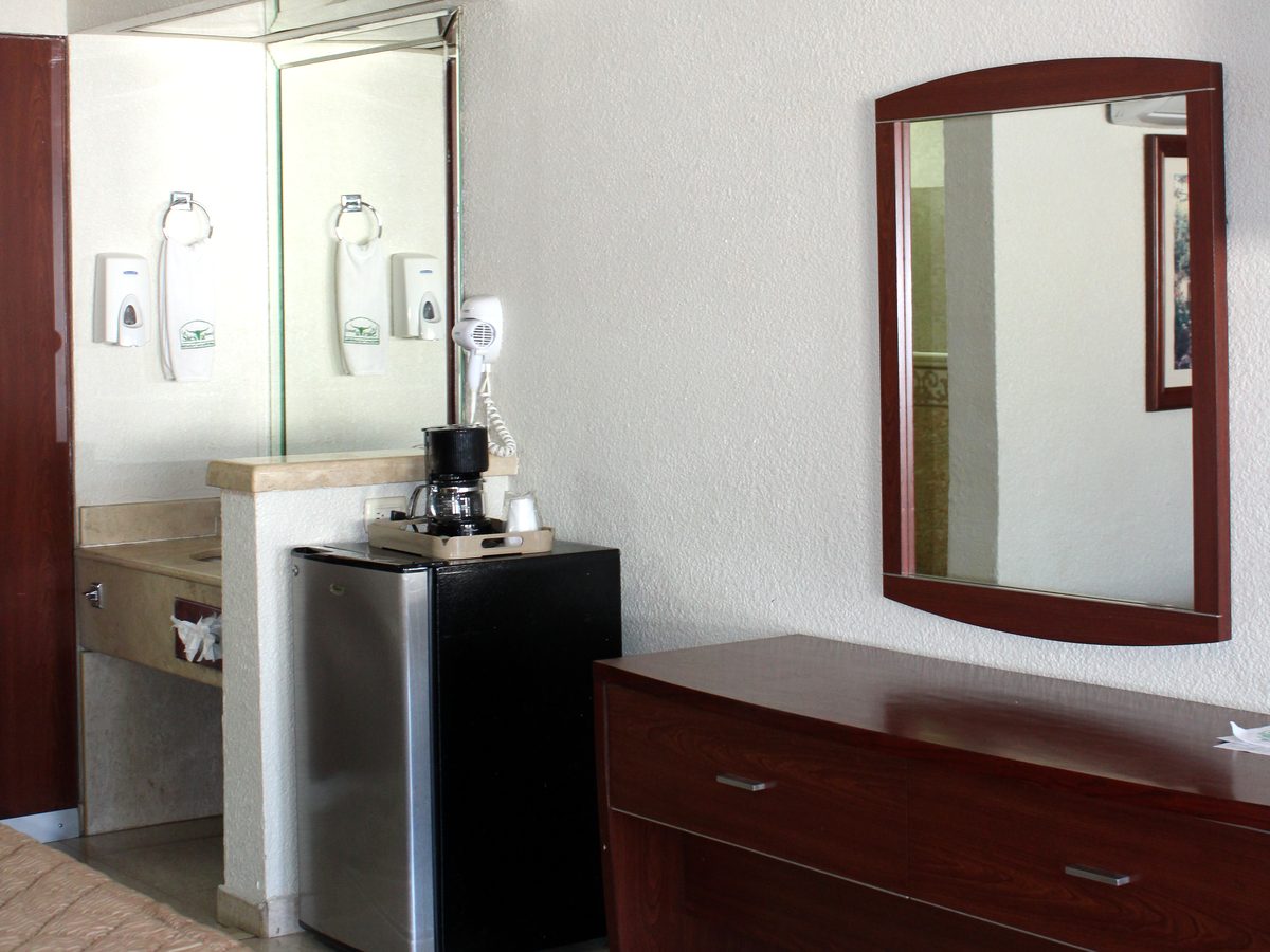Habitación doble clásica: frigobar con cafetera, espejo y cómoda de madera