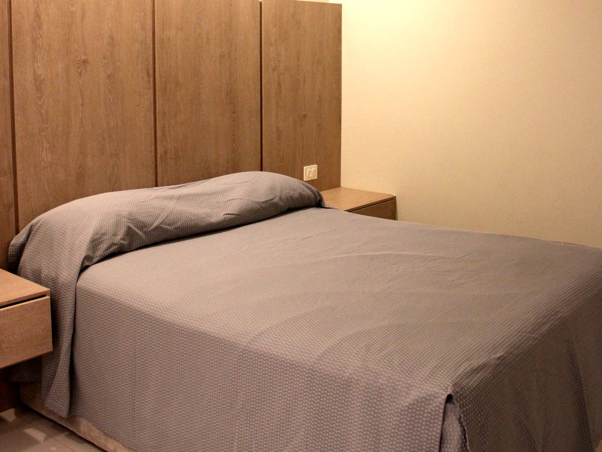 Master Suite: cama con cabecera de madera clara y luz indirecta