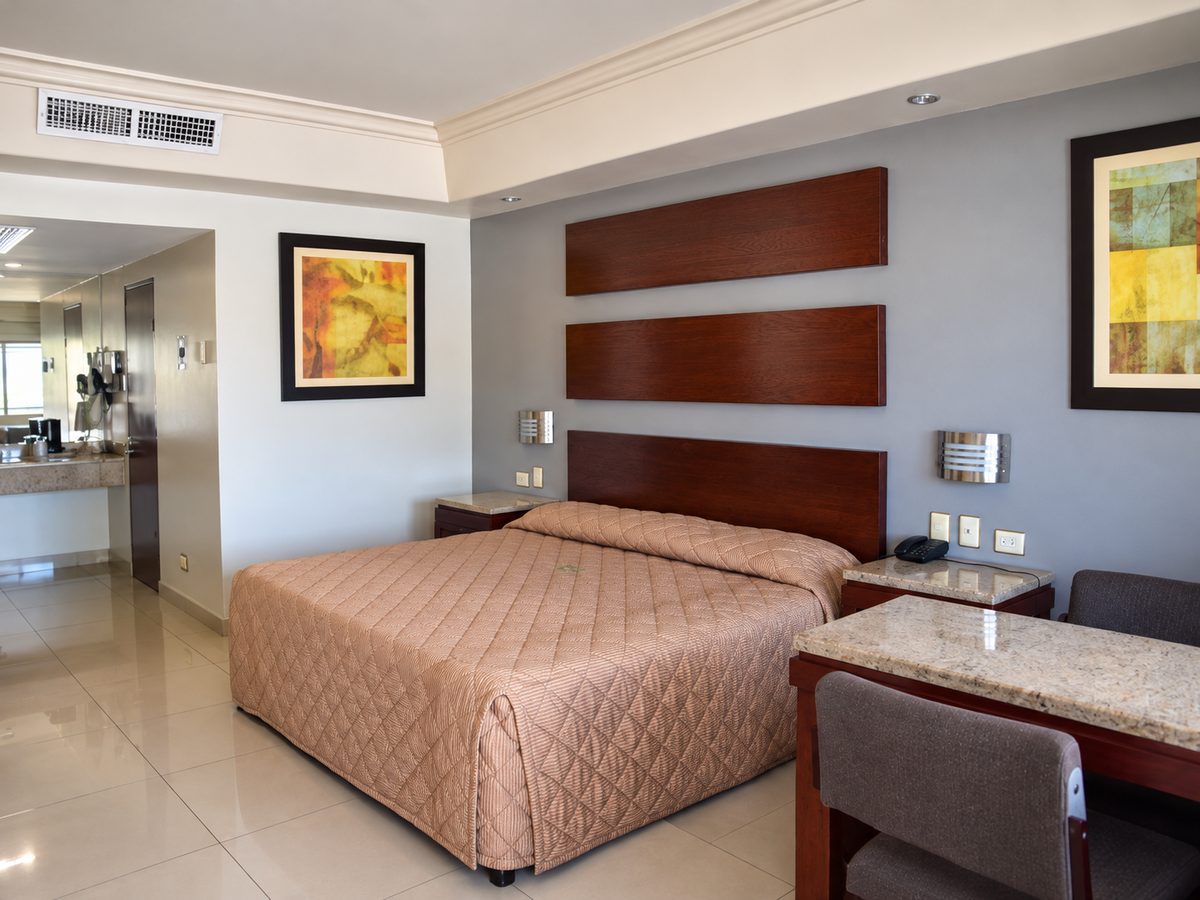 Habitación sencilla: cama King con cabecera de madera, escritorio de granito y el baño al fondo