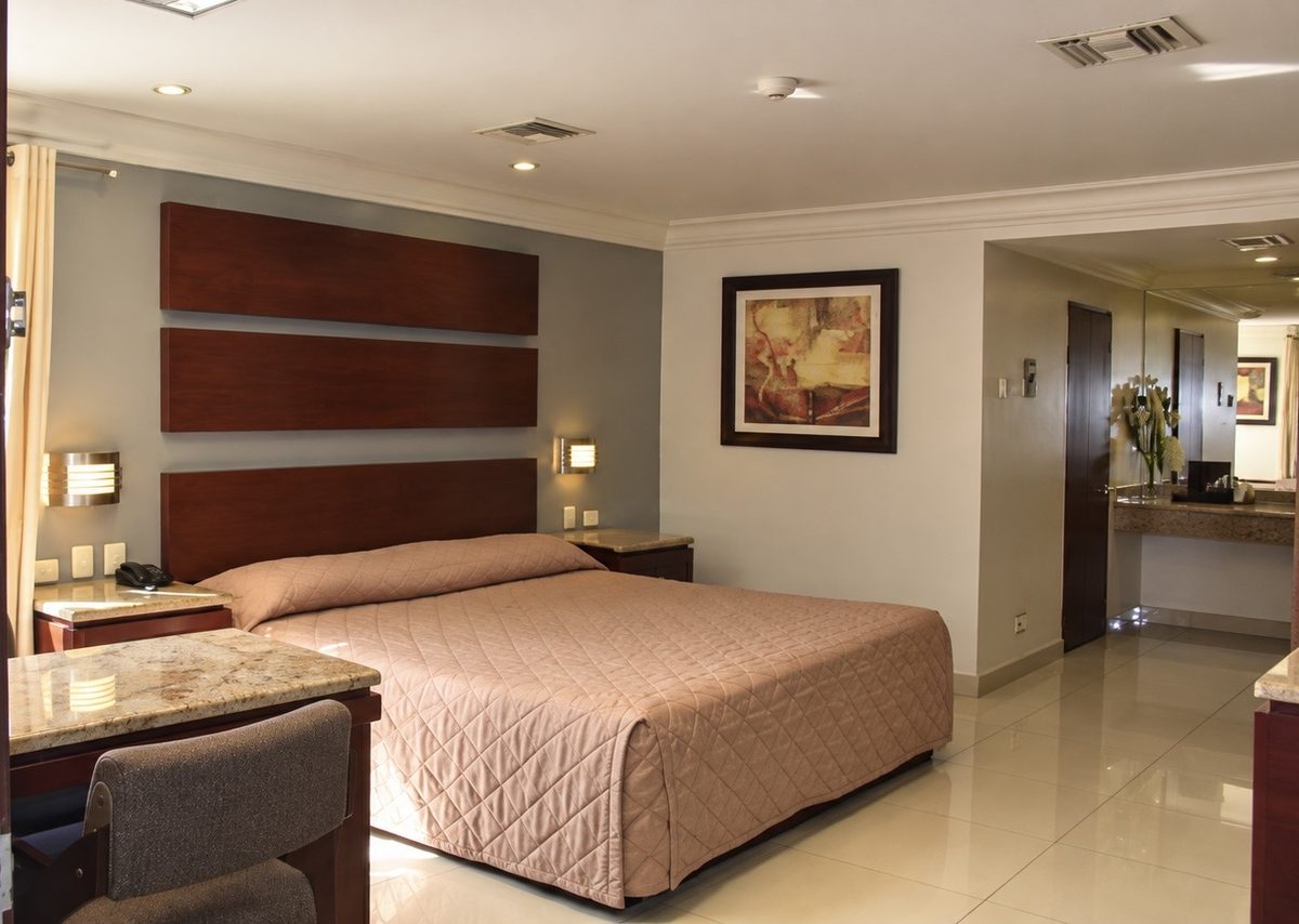 Habitación sencilla: cama King, cabecera de madera y escritorio con silla
