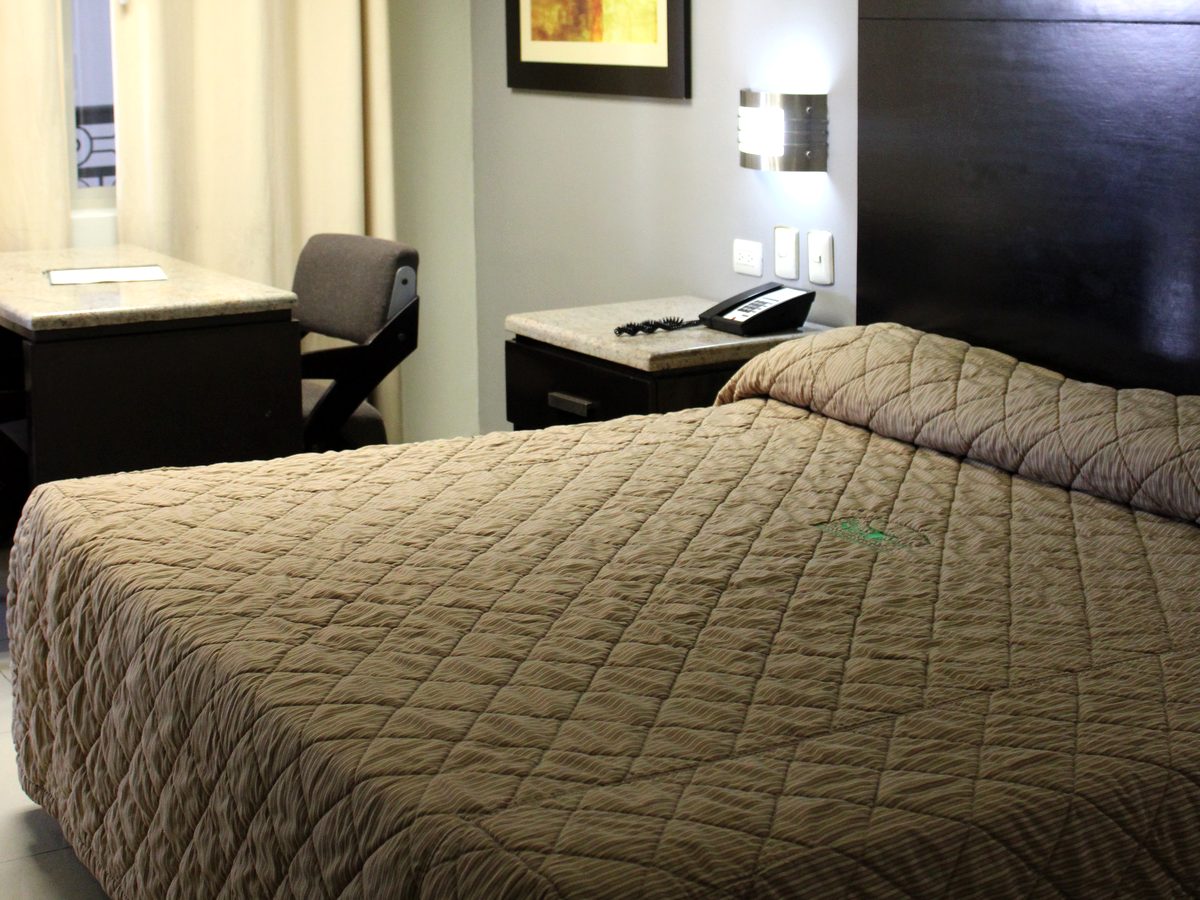 Habitación sencilla: cama King con cabecera oscura, buró de granito y escritorio junto a la ventana